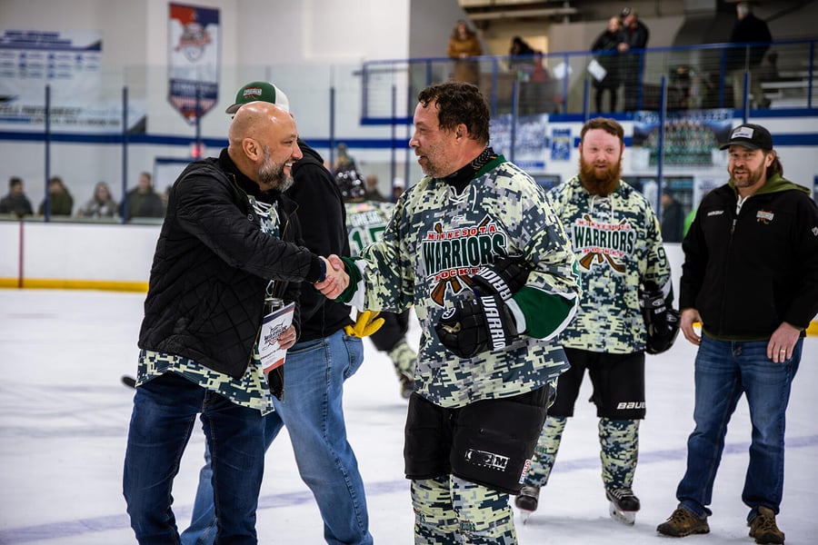 Warriors hockey player shaking anthem singer's hand on the ice