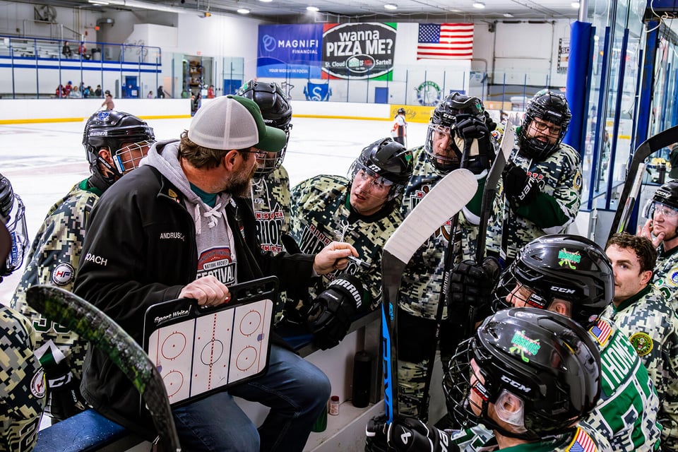 Warriors hockey team in a huddle listening to their coach