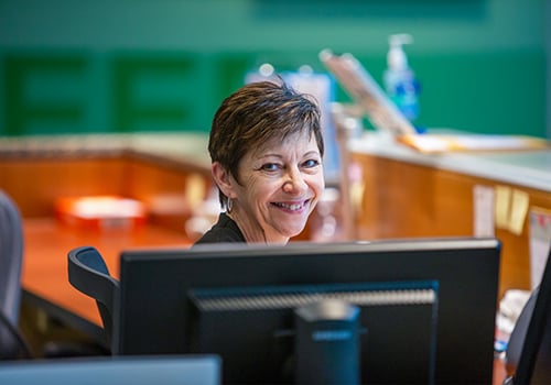 woman smiling behind computer